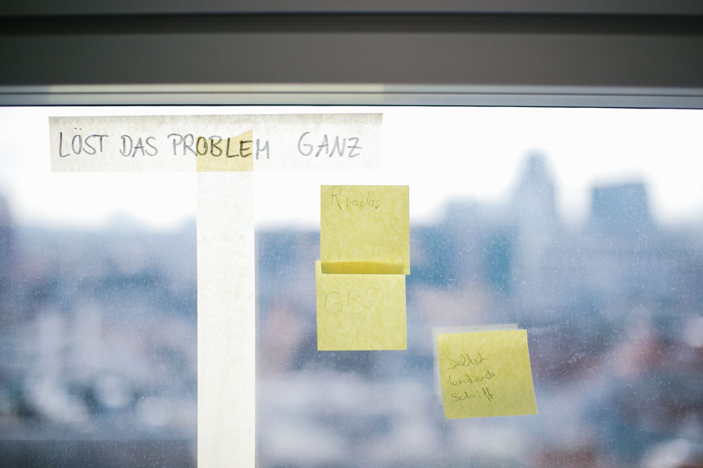 Haftnotizen an einer Fensterscheibe, darüber der handgeschriebene Satz „Löst das Problem ganz“.